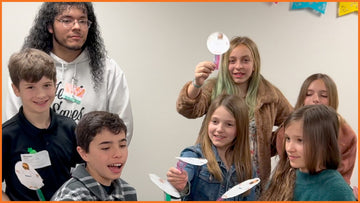 Children showing off Spyence take-home projects that encourage inviting friends